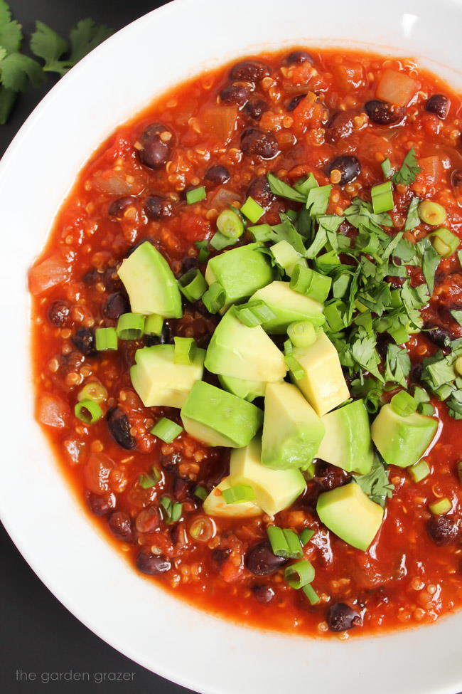 Chipotle black bean quinoa chili in a bowl topped with avocado