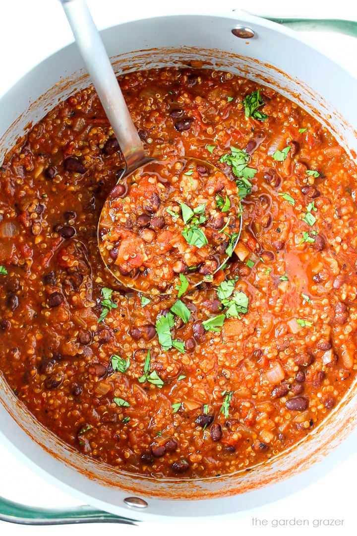 Overhead view of chipotle black bean quinoa chili cooking in a large pot with ladle