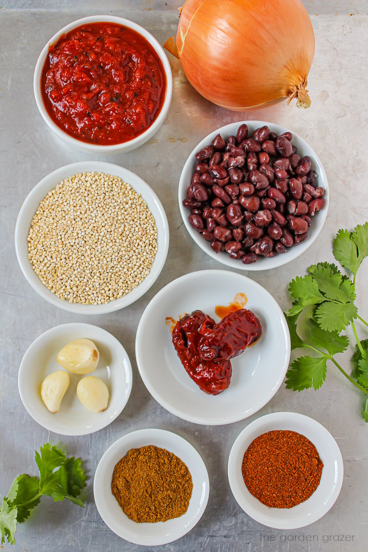 Quinoa, beans, crushed tomatoes, onion, garlic, chipotle, and spice ingredients laid out on a metal tray