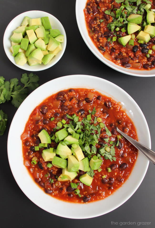 Bowls of smoky chipotle black bean chili with spoon and fresh avocado