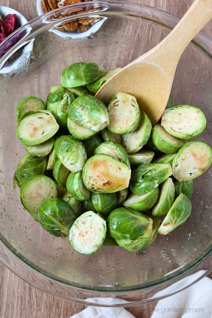 Overhead view of preparing Brussels sprouts in a mixing bowl with balsamic maple miso sauce