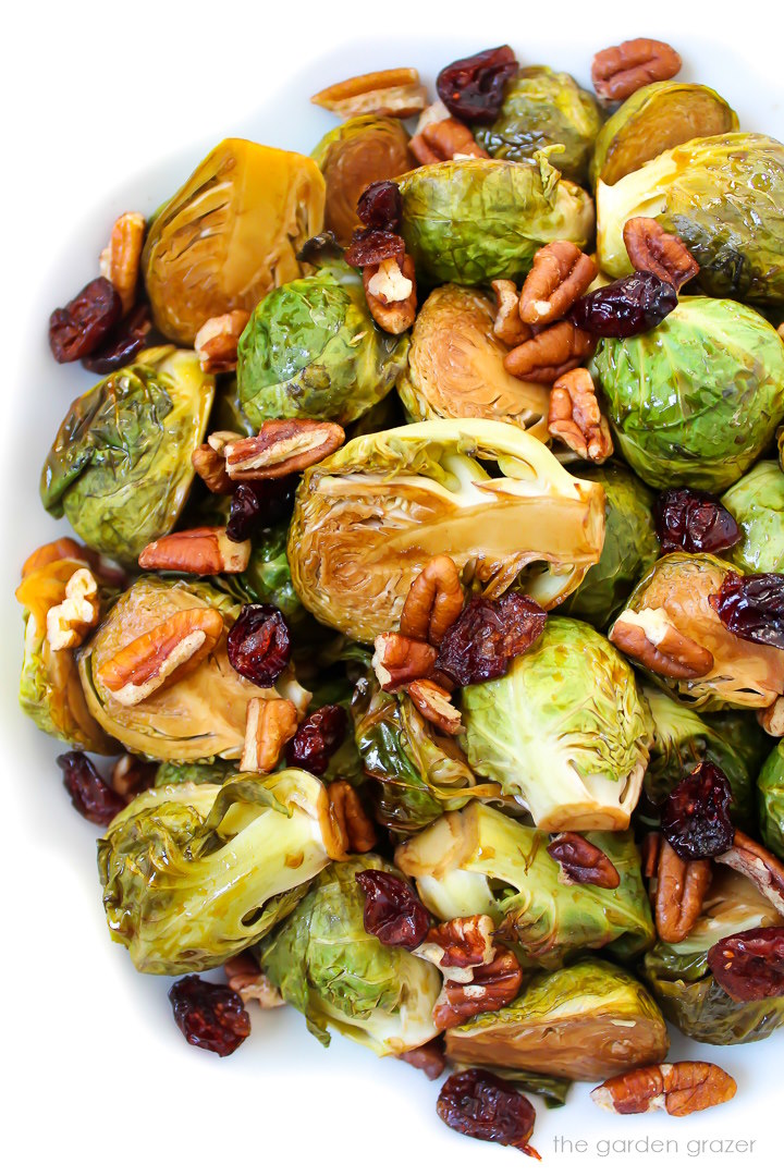 Maple balsamic glazed Brussels sprouts with dried cranberries and pecans on a white plate