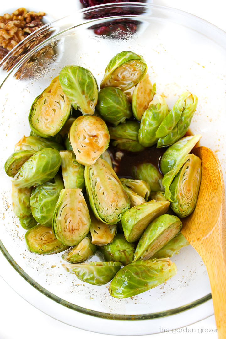 Overhead view of preparing brussels sprouts in a maple balsamic glaze before roasting