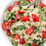 orzo tomato spinach salad in a bowl with spoon