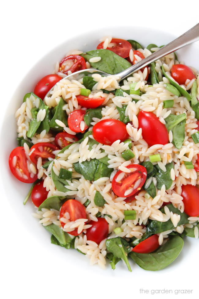 orzo tomato spinach salad in a bowl with spoon
