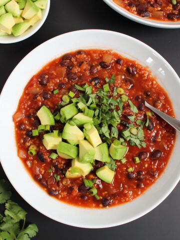 Quinoa black bean chili in a white bowl with spoon