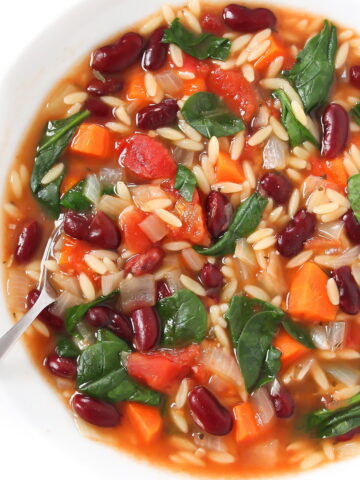 Kidney bean spinach orzo soup in white bowl