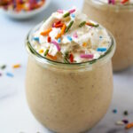 Close up view of birthday cake batter shake in a small glass serving jar with whipped cream and sprinkles