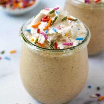 Close up view of birthday cake batter shake in a small glass serving jar with whipped cream and sprinkles