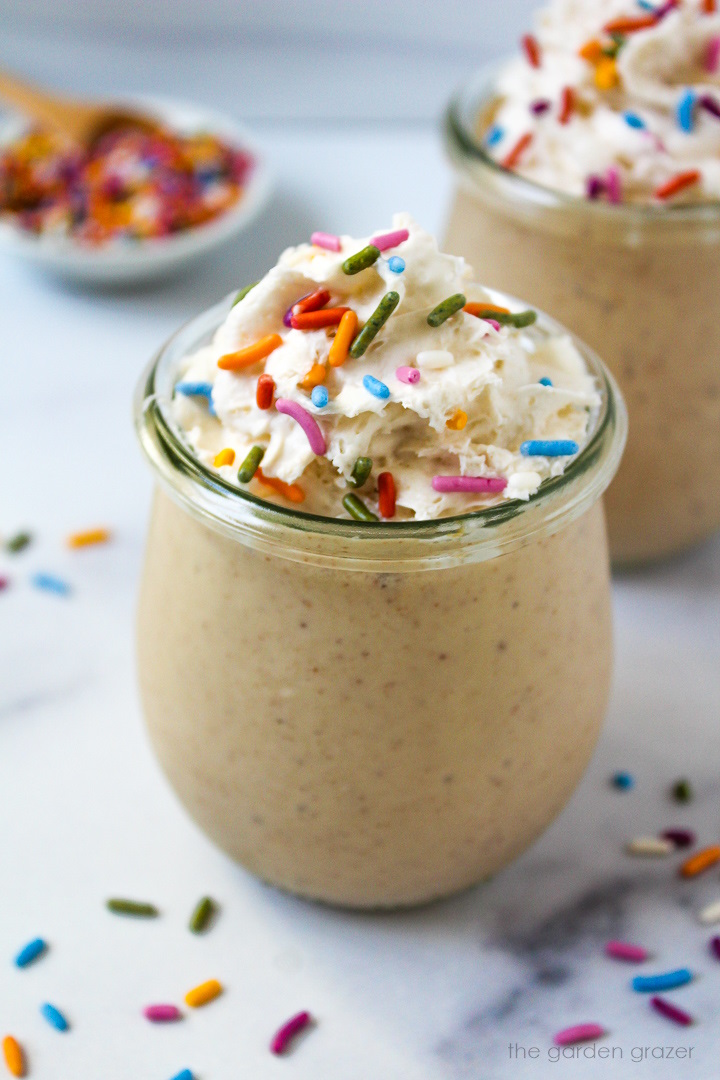 Close up view of birthday cake batter shake in a small glass serving jar with whipped cream and sprinkles