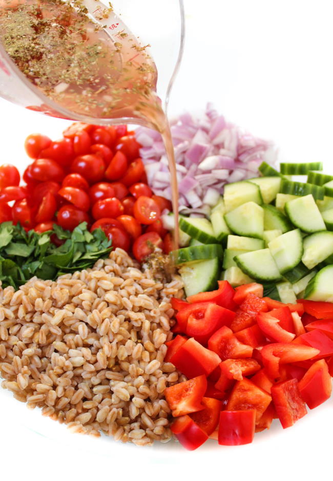 Ingredients in bowl for farro salad with dressing poured over top