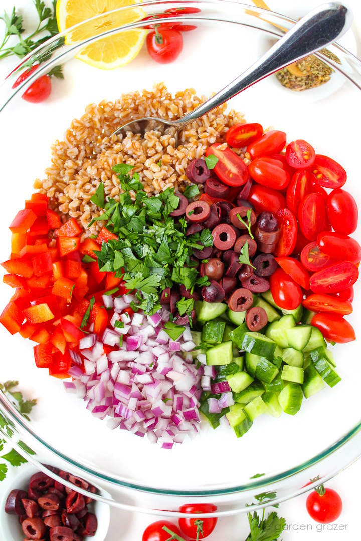 Overhead view of preparing salad ingredients in a large glass bowl before mixing together