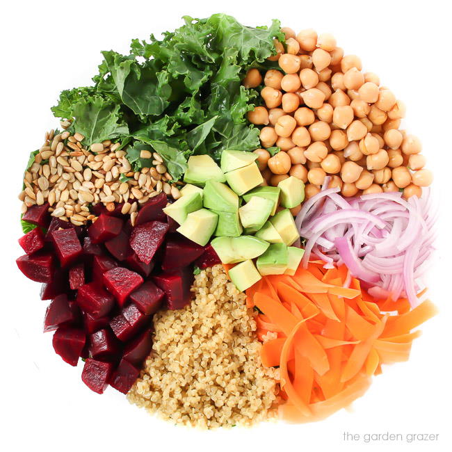 Chickpeas, onion, carrot, beets, quinoa, and leafy greens ingredients in a bowl