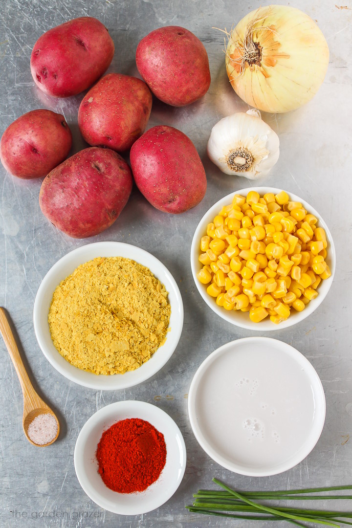 Onion, garlic, nutritional yeast, salt, dairy-free milk, and seasoning ingredients laid out on a metal tray