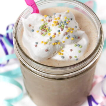 Vegan Cake Shake in a glass with straw and coconut whipped cream