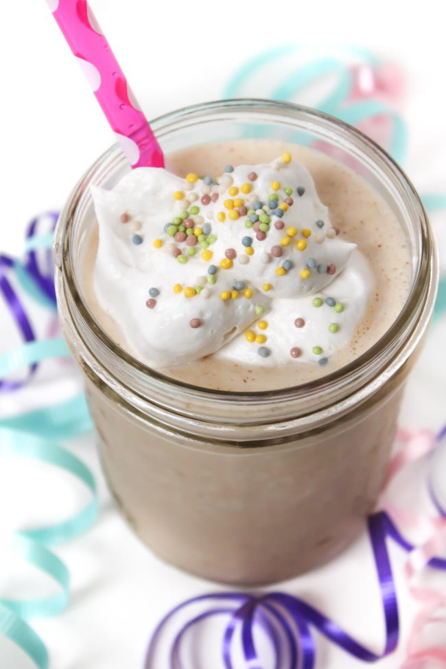 Vegan Cake Shake in a glass with straw and coconut whipped cream