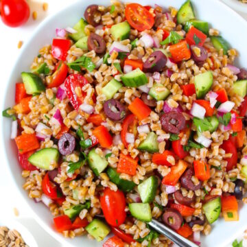 Vegan Greek Farro Salad in a large white bowl with serving spoon