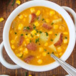 Vegan potato corn chowder served in a white bowl on a wooden table