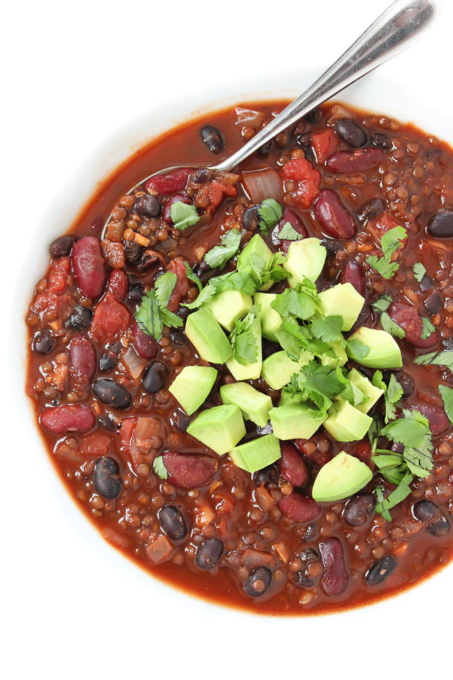 Beluga Lentil Chili in a bowl with spoon and topped with avocado