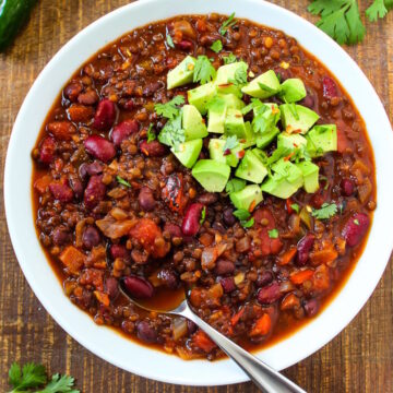 Black lentil chili in a white serving bowl on a wooden table