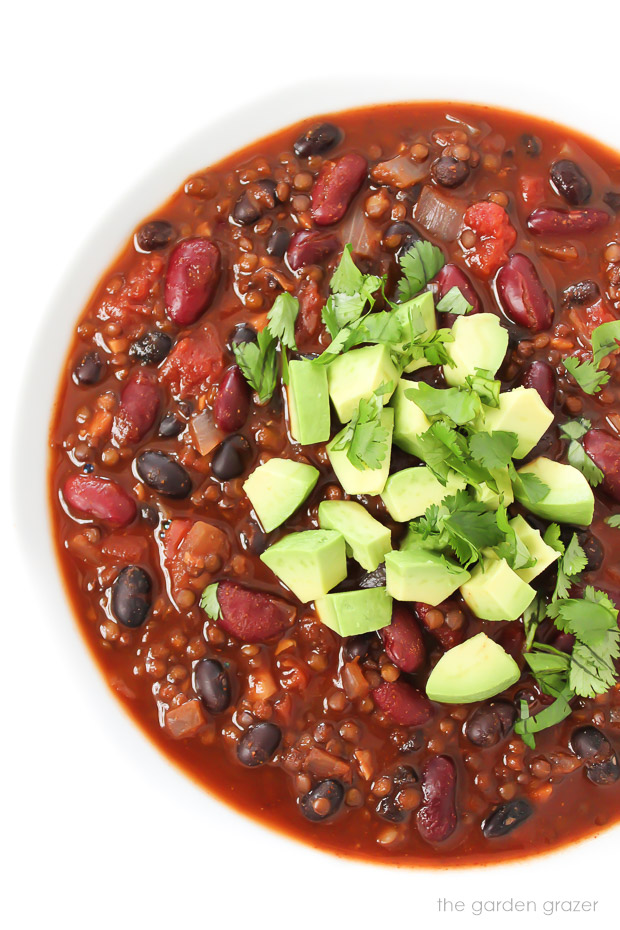 Bowl of vegan beluga lentil chili topped with avocado and cilatnro