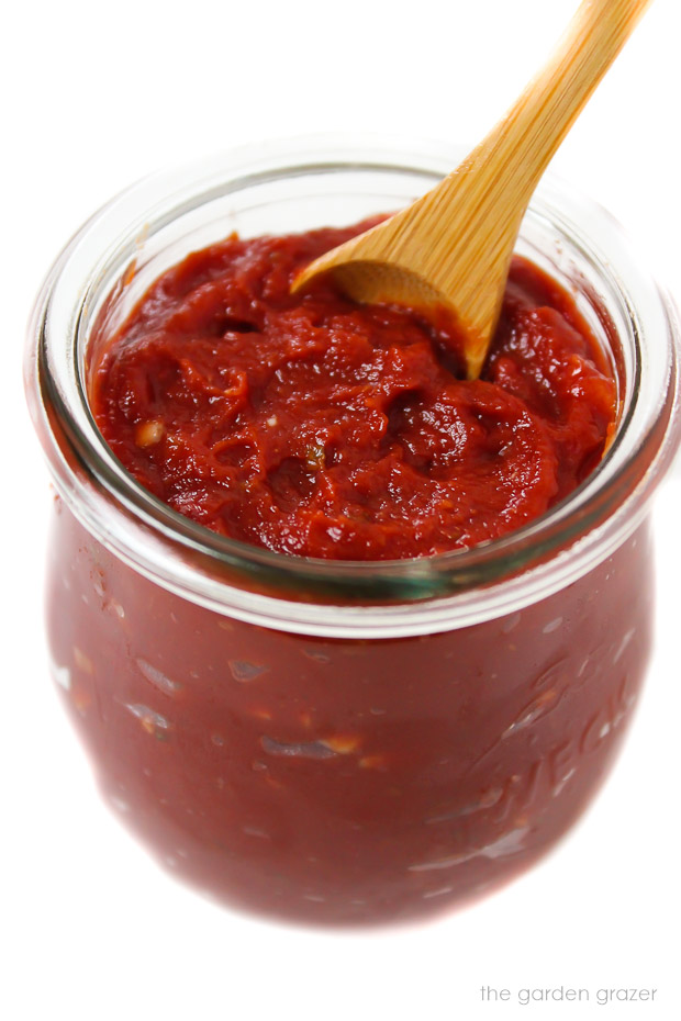 Prepared homemade pizza sauce in a small jar with spoon