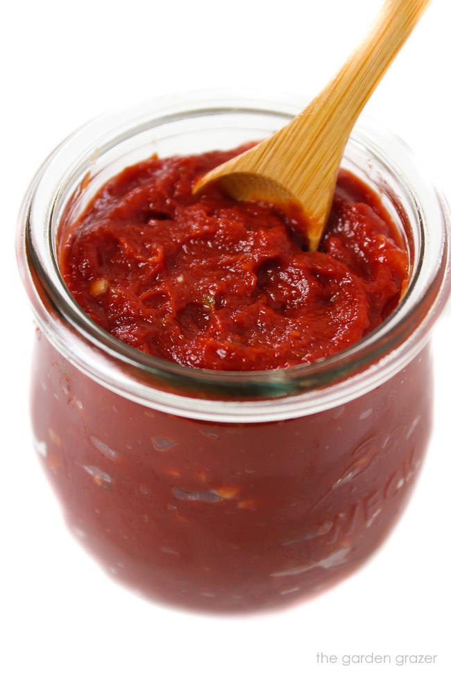 Prepared homemade pizza sauce in a small jar with spoon