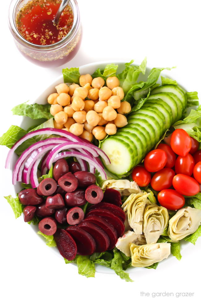 Loaded Greek Salad in a bowl with jar of dressing