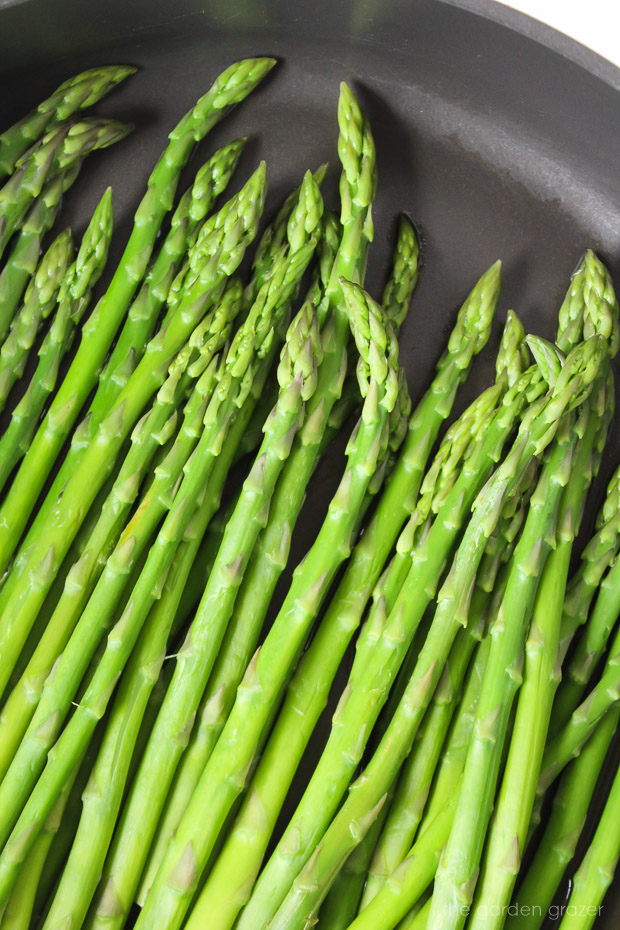 Fresh asparagus spears steaming in a pan on the stove