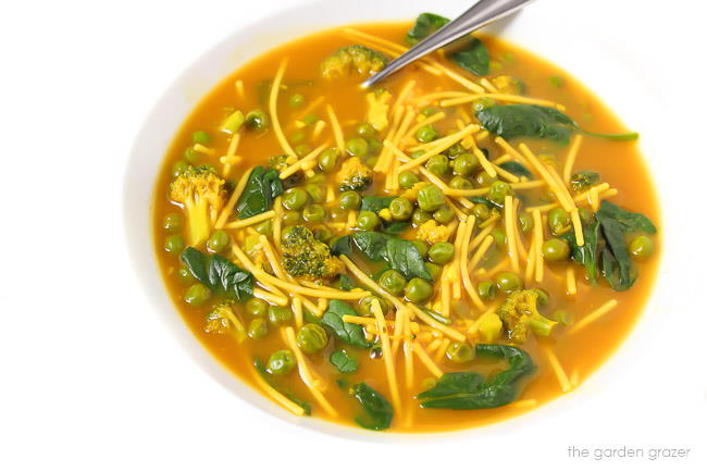 Bowl of vegan noodle soup with spinach, peas, and broccoli