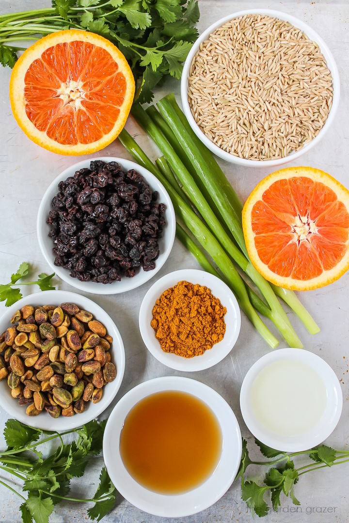 Rice, currants, pistachios, cilantro, green onion, and spice ingredients laid out on a metal tray