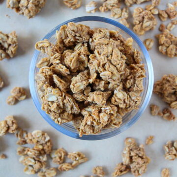 Oil-free peanut butter granola in a glass bowl and scattered around on a tray