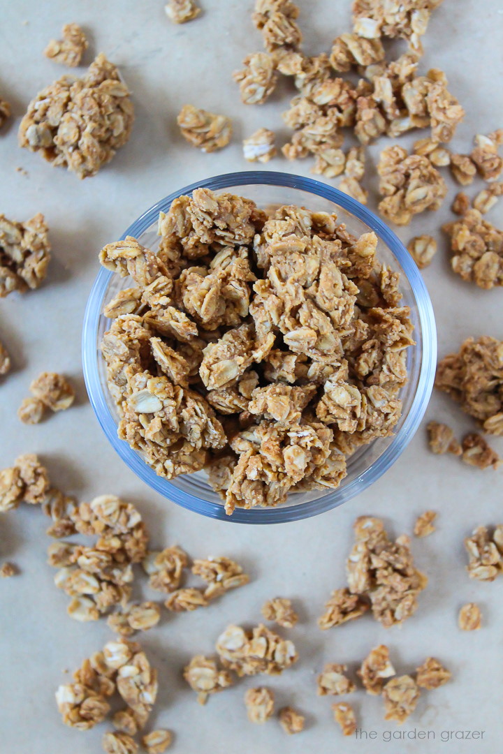 Oil-free peanut butter granola in a glass bowl and scattered around on a tray