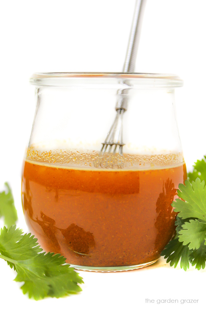 Curry orange dressing in a small glass jar with whisk