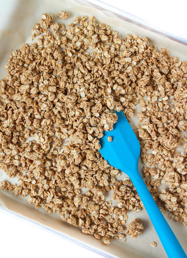Baked granola on a sheet pan with spatula