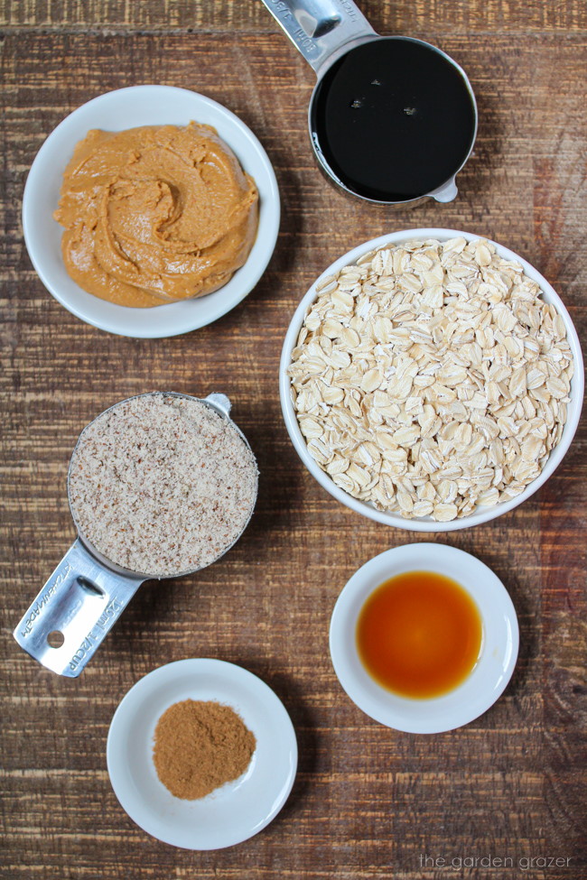 Maple syrup, oats, almond flour, cinnamon, and vanilla ingredients on a wooden table