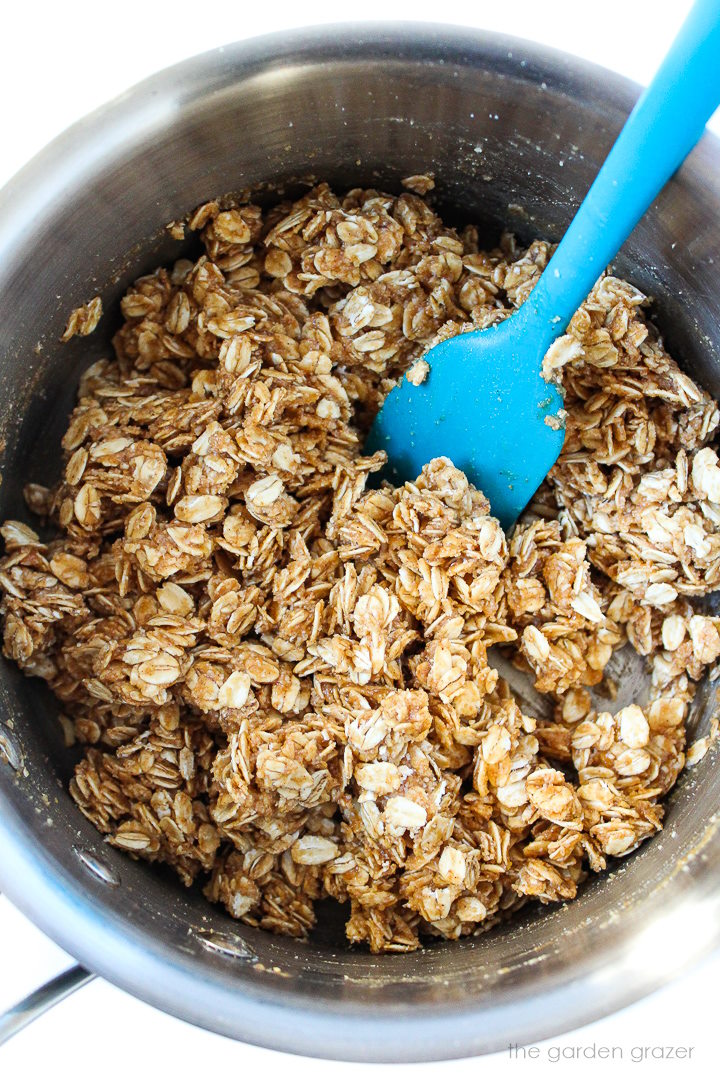 Overhead view of peanut butter granola ingredients mixed together in a saucepan before baking
