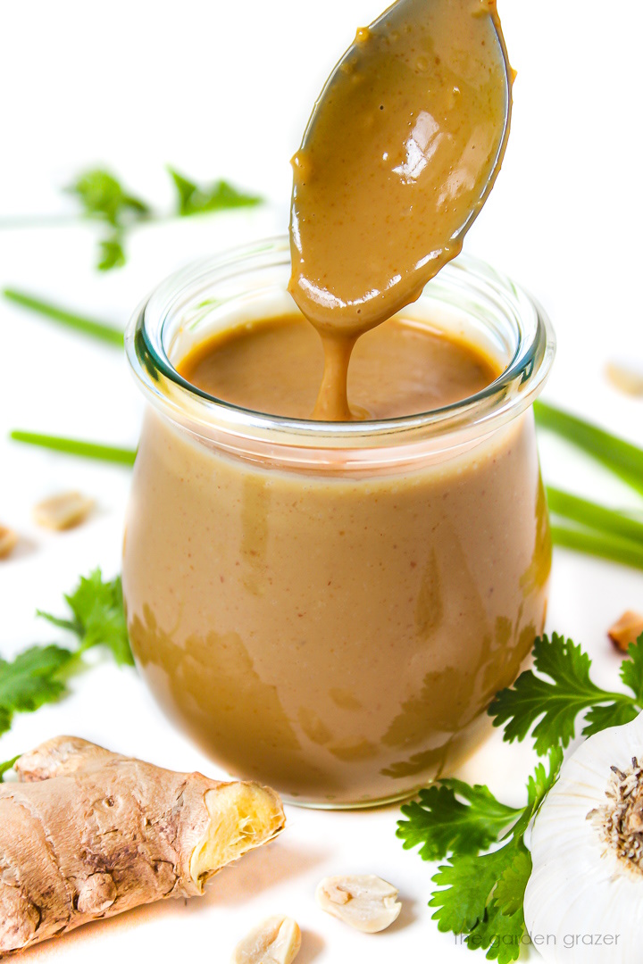 Vegan peanut sauce in a small glass jar with serving spoon
