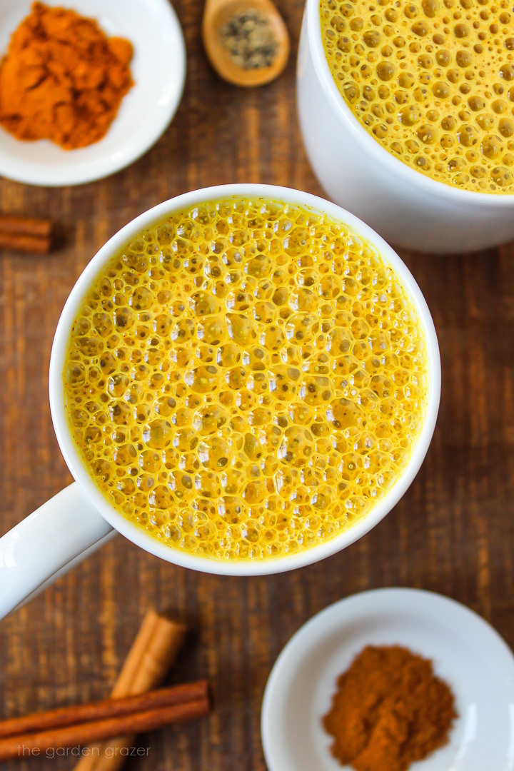 Overhead view of vegan golden milk turmeric latte served in a white mug on a wooden table