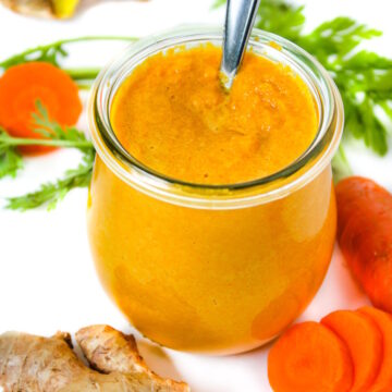 Carrot ginger miso dressing in a small glass jar with serving spoon