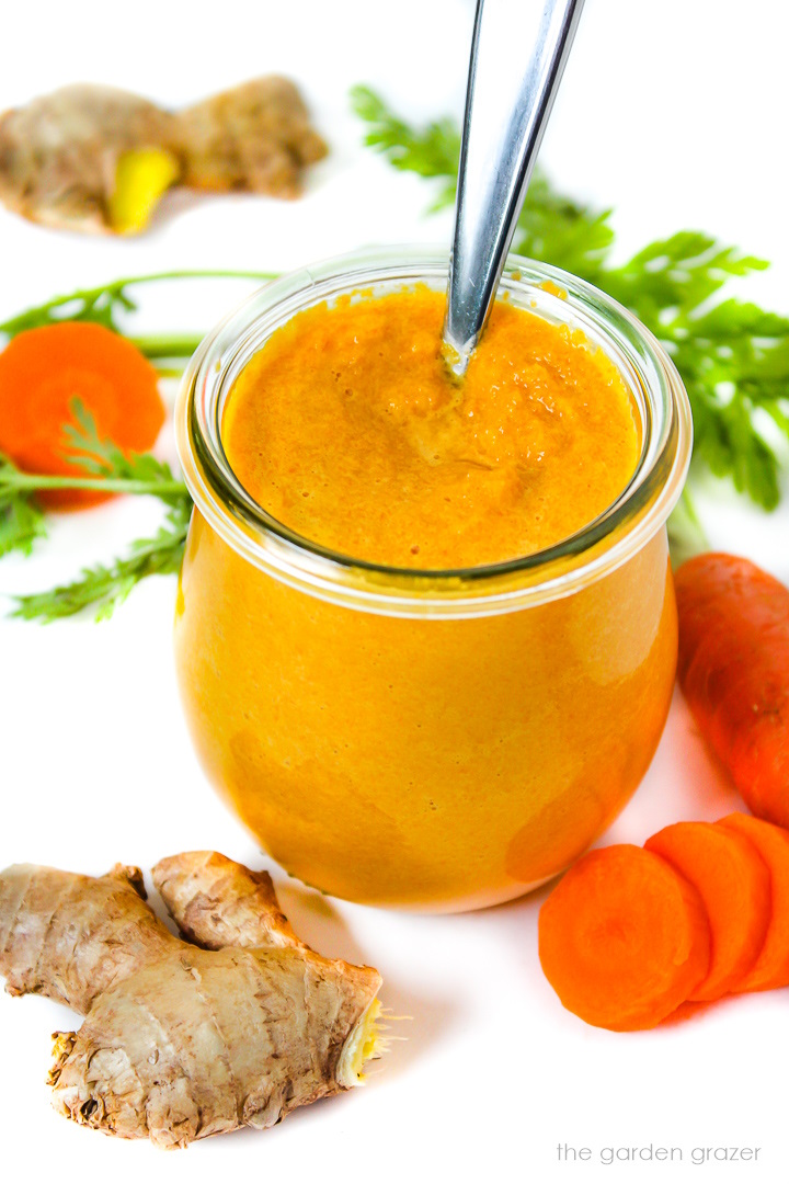 Carrot ginger miso dressing in a small glass jar with serving spoon