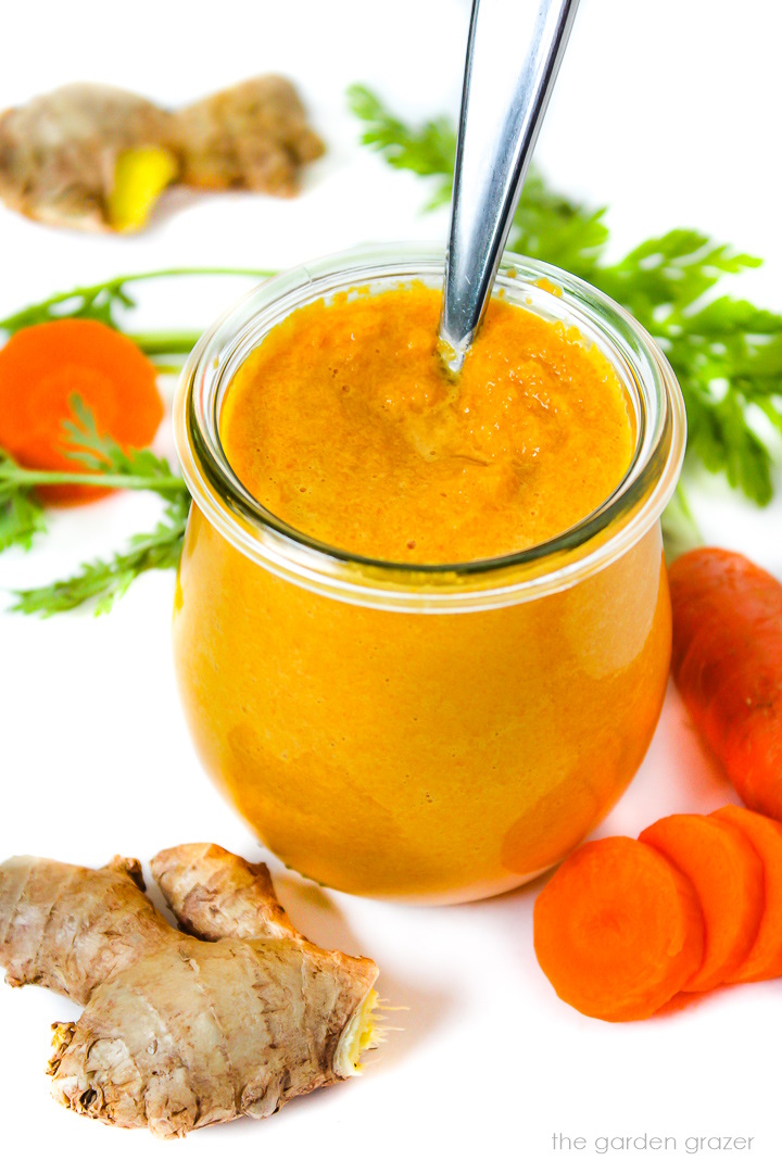 Carrot ginger miso dressing in a small glass jar with serving spoon