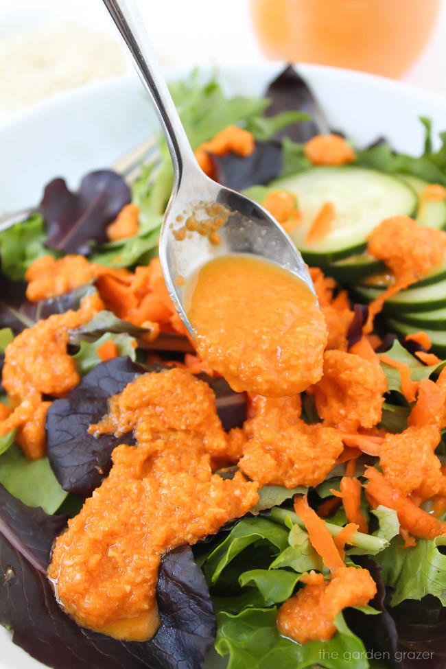 Close up of dressing being drizzled over lettuce with spoon