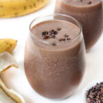 Two chunky monkey protein smoothies in a glass topped with cacao
