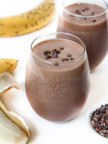 Two chunky monkey protein smoothies in a glass topped with cacao