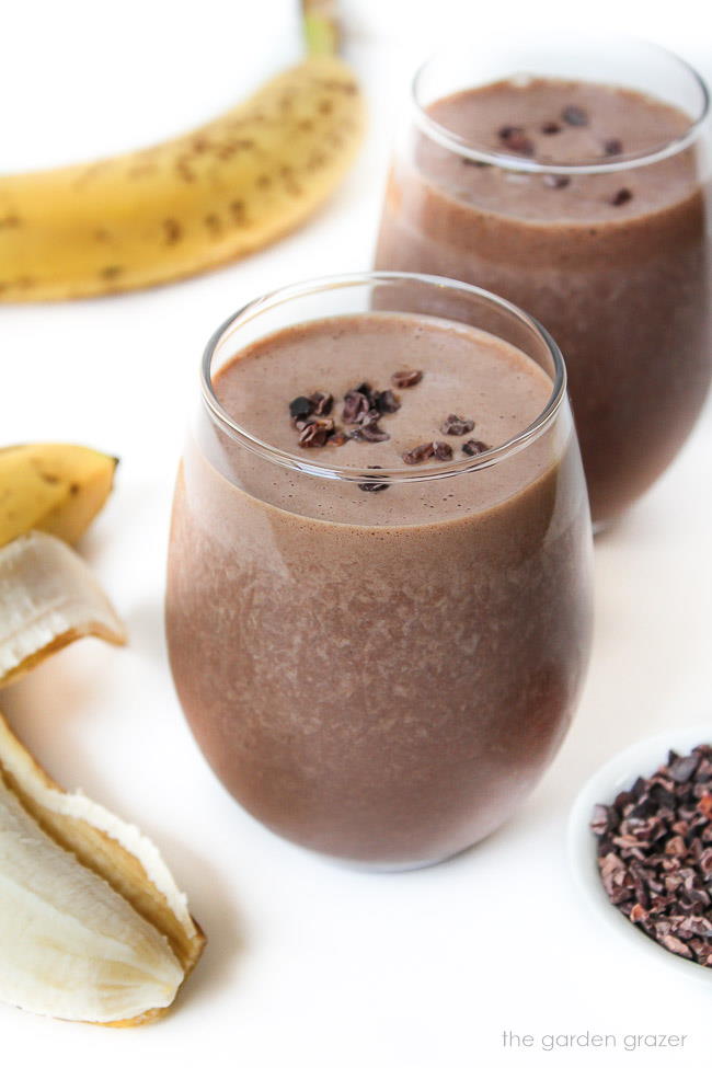 Two chunky monkey protein smoothies in a glass topped with cacao