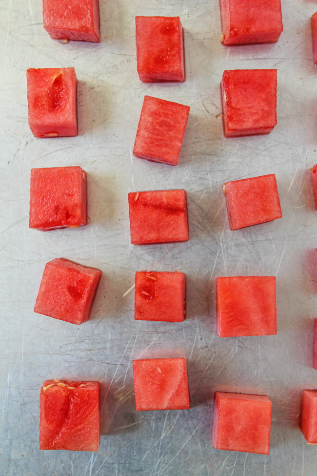 Fresh watermelon cubes on a baking sheet to be frozen