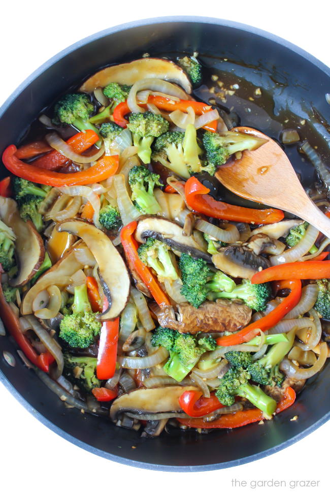 Cooked vegetables and mushrooms in a pan with wooden spoon