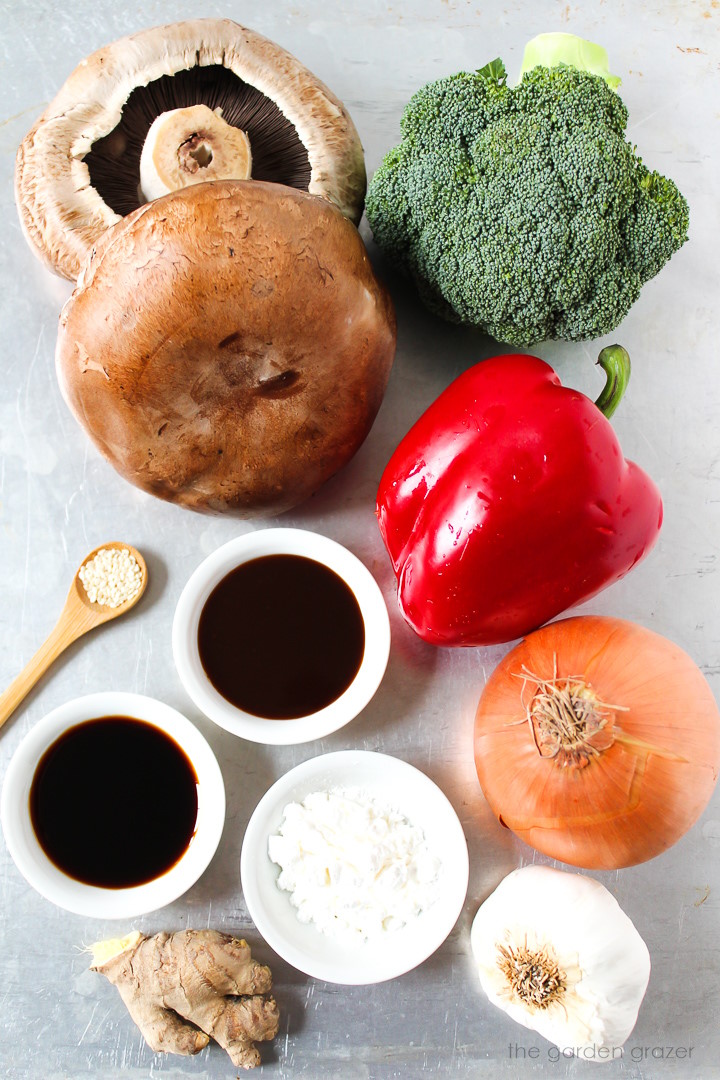 Broccoli, red bell pepper, onion, garlic, ginger, and tamari ingredients laid out on a metal tray