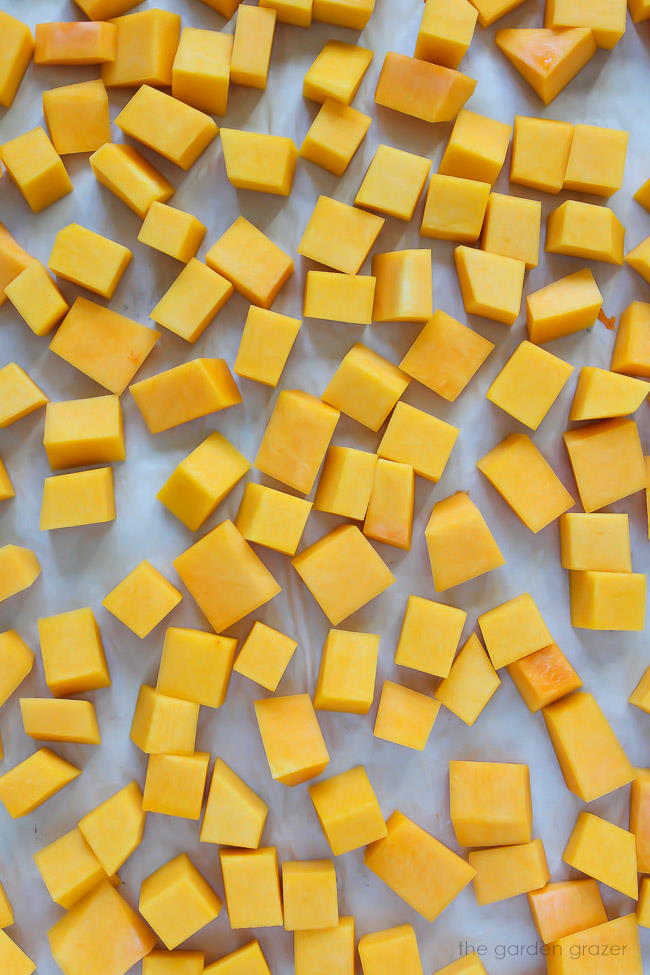 Raw butternut squash cubes spread on a pan ready to roast